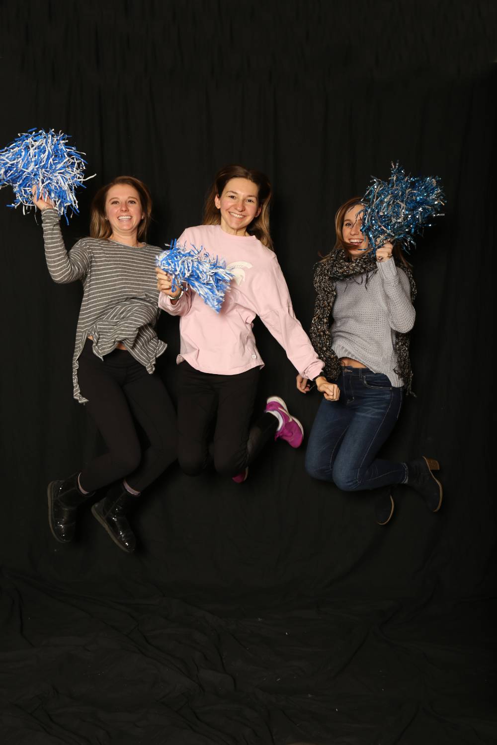 three friends jumping with pom poms